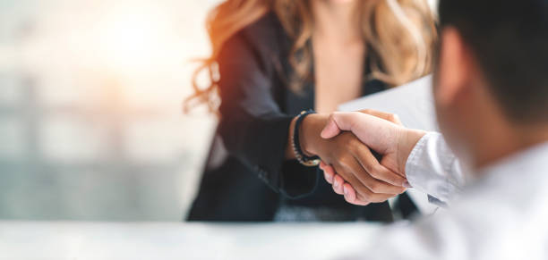 Woman and man shaking hands with blurred background
