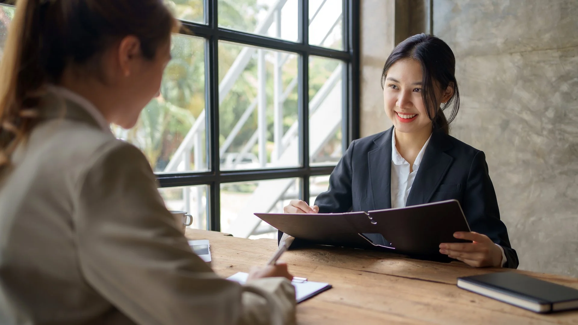 Two woman sitting at desk looking at papers. Human resources administrator.